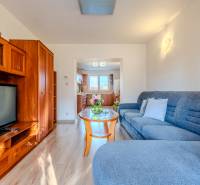 Wohnzimmer in einer Zweizimmerwohnung mit Holzboden und heller Küche.