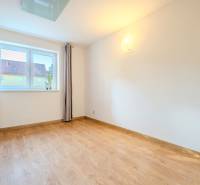 Ein heller Raum mit einem Holzboden in einer 2-Zimmer-Wohnung, Vorhänge und ein Fenster.
