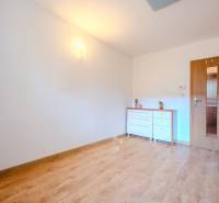 Ein Zimmer in einer 2-Zimmer-Wohnung mit einem Boden in Holzoptik und einer weißen Kommode.