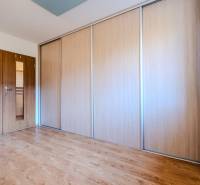 Ein Zimmer in einer 2-Zimmer-Wohnung mit einem Boden in Holzoptik, einem Schrank und einer Kommode.