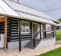 Ein Haus in Legnava mit einer Holzfassade und einer gepflasterten Terrasse, umgeben von Grün und Natur.