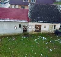 Ein älteres Familienhaus in Klenovec mit einem schrägen Dach auf einem verschneiten Grundstück.