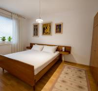 Schlafzimmer in einer 4-Zimmer-Wohnung mit Holzmöbeln, Boden mit Holzdekor und Bildern an der Wand.