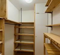 Einfacher Kleiderschrank mit Holzregalen und Kleiderstange in einer 4-Zimmer-Wohnung.