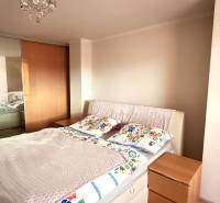 Schlafzimmer mit Bett, Einbauschrank und dekorativem Kronleuchter in einer 3-Zimmer-Wohnung.