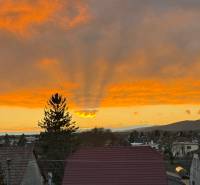 Boleráz bei Sonnenuntergang, man sieht die Dächer der Häuser und einen dramatischen Himmel.