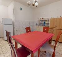 Küche in einem Einfamilienhaus mit weißem Kühlschrank, Mikrowelle und Esstisch.