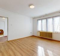 Ein geräumiges Zimmer in einem Einfamilienhaus mit einem Boden in Holzoptik und einem großen Fenster.