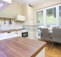 Küche in einer 2-Zimmer-Wohnung mit Holzboden, Esstisch und Geräten.