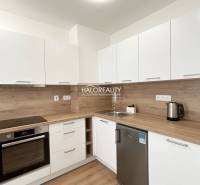 Küche in einer Einzimmerwohnung mit Holzboden und weißen Schränken.