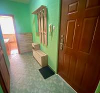 Flur mit grünen Wänden, Fliesenboden, Garderobe und Schränken in einer 3-Zimmer-Wohnung.