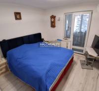 Schlafzimmer mit Bett, Fernseher, Holzboden und Balkontüren in einem Einfamilienhaus.