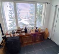 Ein Zimmer mit einem großen Fenster, einer dekorativen Kommode und verschiedenen Gegenständen in einem Einfamilienhaus.