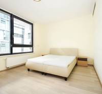 Schlafzimmer mit Bett, Nachttischen und großen Fenstern, Boden mit Holzdekor.