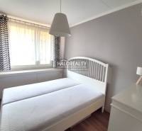 Schlafzimmer in einer 2-Zimmer-Wohnung mit weißen Möbeln und zarten Vorhängen.