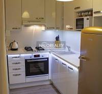 Küche in einer 2-Zimmer-Wohnung mit weißen Schränken und einem Boden in Holzoptik.