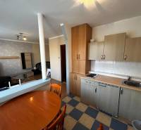 Küche mit Esstisch in einer Einzimmerwohnung, Boden mit Holzdekor.