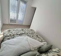 Helles Schlafzimmer in einer 2-Zimmer-Wohnung mit dekorativen Kissen und Holzboden.