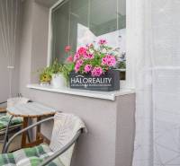 Ein Balkon einer 3-Zimmer-Wohnung mit Blumen und einem Tisch, geeignet zum Entspannen.