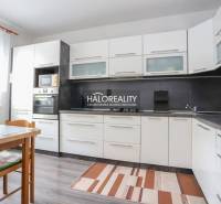 Küche in einer 3-Zimmer-Wohnung mit weißen Schränken und einem Boden in Holzoptik.