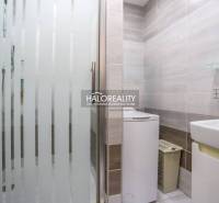 Badezimmer mit Waschmaschine und Duschkabine in einer 3-Zimmer-Wohnung, helle Fliesen, sauberes Design.