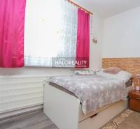 Ein Zimmer in einer 3-Zimmer-Wohnung mit einem Bett, einem Blumenvorhang und einem Boden mit Holzdekor.