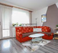 Wohnzimmer in einer 3-Zimmer-Wohnung mit einem orangefarbenen Sofa und einem Boden in Holzoptik.