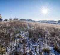 Ein verschneites Grundstück in Mlynica mit Wohnhäusern im Hintergrund, ideal zum Wohnen.