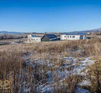 Grundstücke zum Wohnen in Mlynica mit Panoramablick und modernen Gebäuden im Hintergrund.