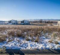 Verschneite Wohngebiete in Mlynica mit sonnigem Wetter und sichtbaren Häusern im Hintergrund.