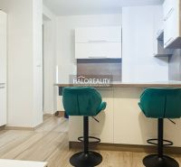 Küche in einer 2-Zimmer-Wohnung mit türkisfarbenen Stühlen und Holzboden.