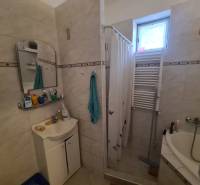 Badezimmer im Einfamilienhaus, Duschkabine mit Vorhang, Waschbecken, Spiegel und Heizkörper.