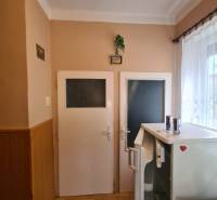 Innenraum eines Einfamilienhauses mit zwei Türen, einem Kühlschrank und einem Boden mit Holzdekor.