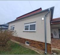 Ein Einfamilienhaus in Hurbanovo mit heller Fassade und rotem Dach, umgeben von Sträuchern.