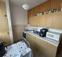 Küche in einer 2-Zimmer-Wohnung mit Holzdekor, einschließlich Geräten und Esstisch.