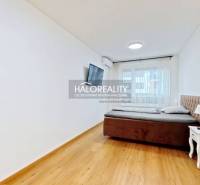 Schlafzimmer in einer 2-Zimmer-Wohnung mit Bett, Nachttisch und Fernseher, hat einen Boden mit Holzdekor.