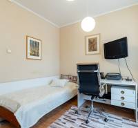 Ein Zimmer in einer 4-Zimmer-Wohnung mit einem Bett, einem Schreibtisch und einem Fernseher an der Wand.