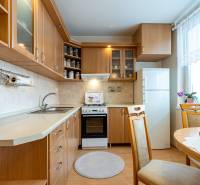 Küche mit hellen Möbeln, Boden mit Holzdekor, Esstisch.