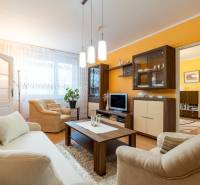 Wohnzimmer in einer 4-Zimmer-Wohnung mit Sofa, Sesseln und Boden in Holzoptik.