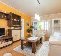 Wohnzimmer in einer Vierzimmerwohnung mit Holzboden und orangefarbener Wand.