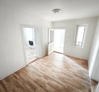 Ein Zimmer in einem Einfamilienhaus mit einem Holzboden und einfacher Einrichtung.