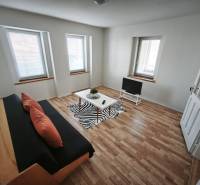 Wohnzimmer in einem Einfamilienhaus mit Sofa, Fernseher und Holzboden.