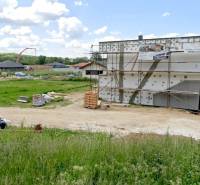 Baugrundstück zum Wohnen in Modrovka mit einem im Bau befindlichen Gebäude und Umgebung im Hintergrund.