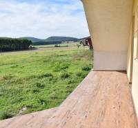 Ein Einfamilienhaus in Buková mit Terrasse und Boden in Holzoptik, Blick auf die Felder.