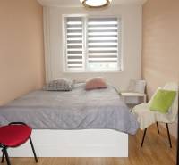 Schlafzimmer in einer 3-Zimmer-Wohnung mit Bett, Sesseln und Boden in Holzoptik.