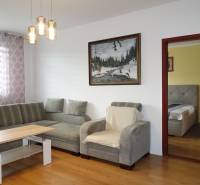 Wohnzimmer in einer 3-Zimmer-Wohnung mit Sofa, Sessel und Boden in Holzoptik.