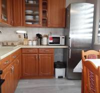 Küche mit Holzdekor, Herd, Kühlschrank und Esstisch in einer 3-Zimmer-Wohnung.