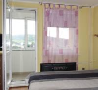 Schlafzimmer mit Zugang zum Balkon in einer 3-Zimmer-Wohnung mit lila Vorhängen am Fenster.