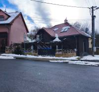 Ein Einfamilienhaus in der Rudlovská-Straße in Banská Bystrica mit rotem Dach und Schnee.