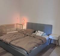 Schlafzimmer mit gepolstertem Bett, Kinderbett und Nachttisch in einer 4-Zimmer-Wohnung.